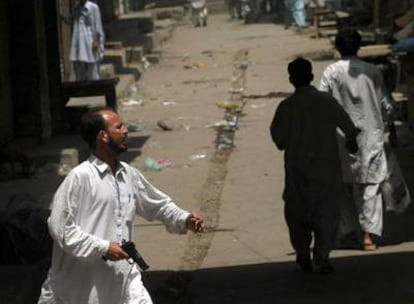 Un hombre camina ayer, pistola en mano, por el barrio de Karachi donde se registraron nuevos enfrentamientos.