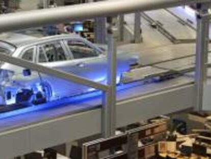 En la imagen, la carrocería de un coche es transportada por una línea de montaje sobre las cabezas de los empleados en la planta que la fabricante de automóviles BMW tiene en Leipzig (Alemania). EFE/Archivo