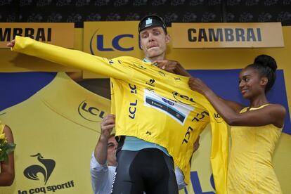 Tony Martin se pone el 'maillot' amarillo con la ayuda de una azafata.