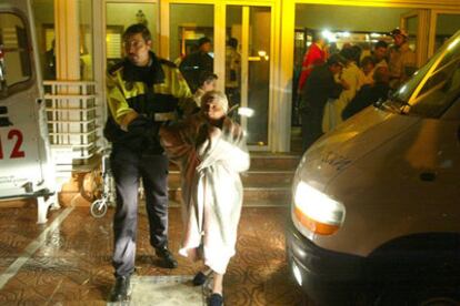 Una mujer es desalojada de la residencia por los servicios de emergencia.