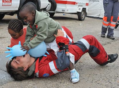 Dos niños llegados en patera ayer a Tarifa juegan con un miembro de la Cruz Roja.