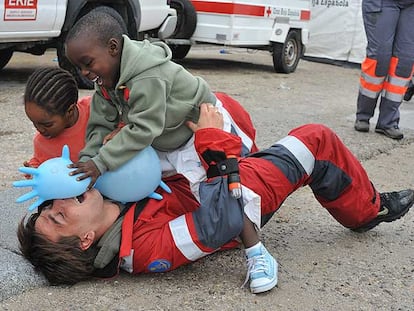 Dos niños llegados en patera ayer a Tarifa juegan con un miembro de la Cruz Roja.