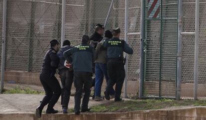 Security forces return a migrant who jumped the fence at Melilla.