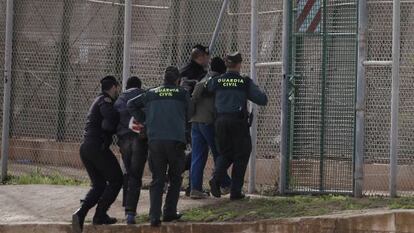 Security forces return a migrant who jumped the fence at Melilla.
