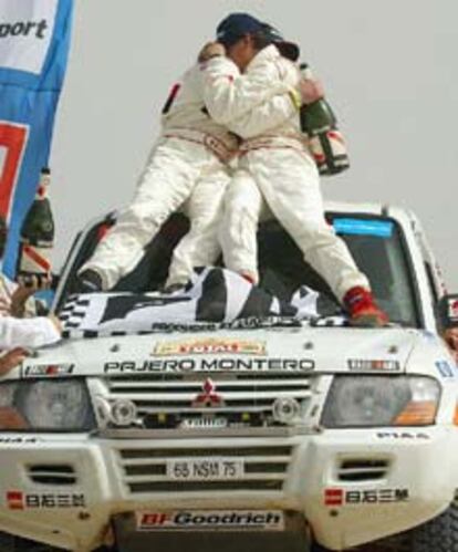 El japonés Hiroshi Masuoka, vencedor en la categoría de coches, se abraza a su copiloto, Pascal Maimon.