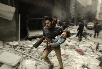 Un hombre corre con un niño en brazos tras el ataque aéreo por fuerzas leales al presidente sirio Bashar El-Assad, en Aleppo 