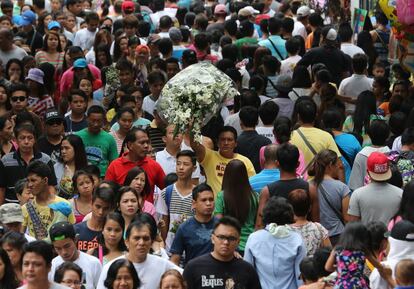 Un hombre lleva un ramo de flores por el cementerio Norte de Manila (Filipinas) abarrotado en el día de Todos los Santos.