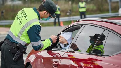 Un agente de la Guardia Civil de Tráfico comprueba la documentación de un conductor en un control policial en la frontera entre Navarra y Álava durante la pandemia.