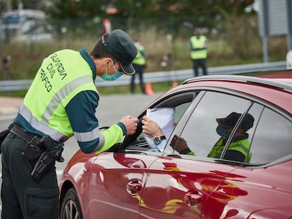 Un agente de la Guardia Civil de Tráfico comprueba la documentación de un conductor en un control policial en la frontera entre Navarra y Álava durante la pandemia.