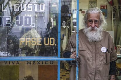 Don Manuel en la puerta de la peluquería. El letrero dice: “Cortes modernos a gusto de usted”.