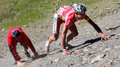 El ciclista sudafricano John Lee Augustyn (Barloworld) es ayudado a subir la colina por la que cayó tras sufrir un accidente.