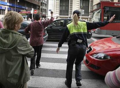 Varios peatones cruzan desesperados por la espera de un semáforo averiado en Valencia.