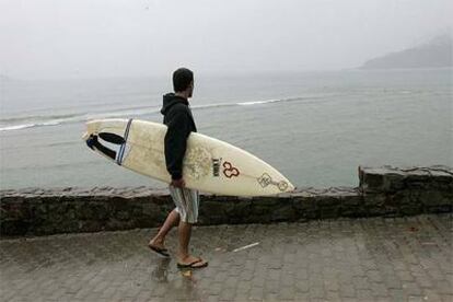 Un surfista pasea con su tabla por Mundaka, meca mundial para los aficionados a este deporte.