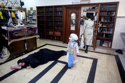 Una niña ultraortodoxa disfrazada pasa al lado de un hombre ebrio tumbado en el suelo durante el carnaval de Purim.