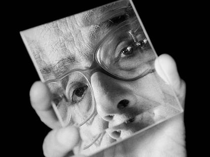 Saramago sostiene un espejo en que se refleja su rostro.