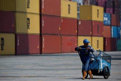 A man pushes a cart past containers at the Tanjung Priok port in Jakarta, Indonesia, on November 4, 2021.