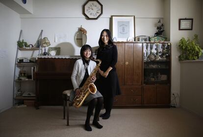 Manami Miyazaki, de 39 años, posa de pie con su hija Nanaha de 13, que aparece con su saxofón, en una de las habitaciones de su casa de Tokio. Manami es ama de casa y estudió hasta los 20 años. Le hubiese gustado tener un trabajo que le permitiese conocer a mucha gente. Espera que su hija forme una familia y le encantaría que Nanaha encontrase un trabajo que le permitiese desarrollar sus habilidades. Nanaha quiere ser diseñadora, música o enfermera.