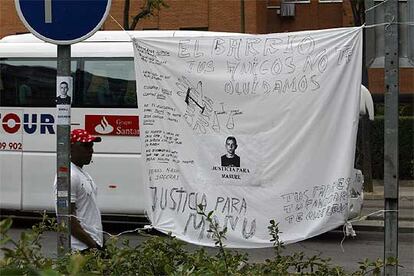 Un inmigrante pasa ante una sbana con pintadas alusivas a la muerte de Manu, en la calle de Villafuerte.