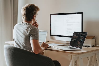 Un hombre teletrabaja en su casa con varios dispositivos.