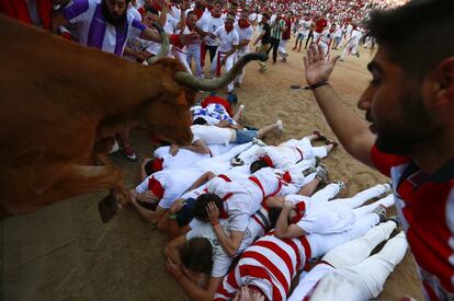 Aficionados taurinos se protegen cuando un becerro salta sobre ellos en la plaza de toros, durante el 4º día de encierros de San Fermín, en Pamplona.