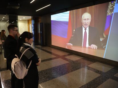 Varios ciudadanos rusos escuchan un mensaje de Vladímir Putin en una pantalla gigante.
