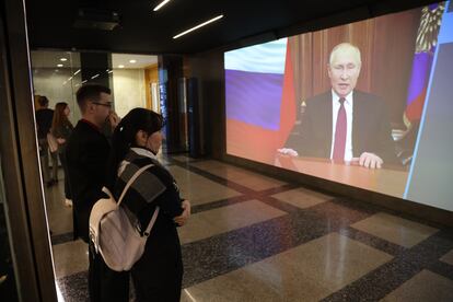 Varios ciudadanos rusos escuchan un mensaje de Vladímir Putin en una pantalla gigante.