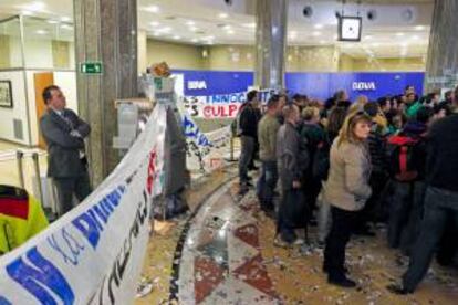 Un trabajador observa a las cerca de 200 personas que han ocupado hoy las oficinas centrales del BBVA en la plaza Cataluña de Barcelona.