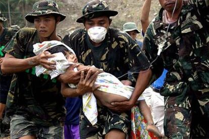 Soldados filipinos rescatan a una niña atrapada entre los escombros en Tigloan, al norte del país.