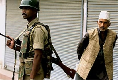 Un musulman de la zona de Cachemira pasa por détrás de un agente de seguridad indio en una calle de Srinagar.