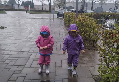 Maia y Milena, vestidas con el traje de lluvia y las botas de agua, vuelven al colegio en Dinamarca.