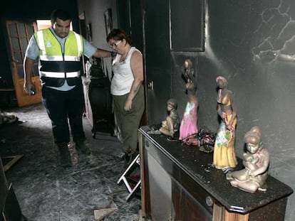 Un agente consuela a la propietaria del restaurante La Fuente, en Masca, que ha quedado destrozado por el fuego.