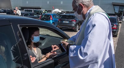 Un sacerdote da la comunión a los fieles durante la celebración de la primera misa en automóvil en Chalons-en-Champagne (Francia).