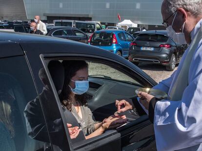 Un sacerdote da la comunión a los fieles durante la celebración de la primera misa en automóvil en Chalons-en-Champagne (Francia).