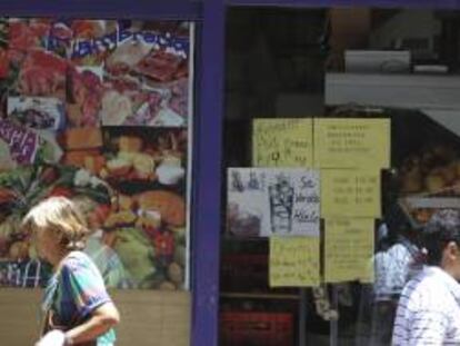 Dos personas caminan frente a un supermercado con avisos de promoción ayer, en el centro de Buenos Aires (Argentina).