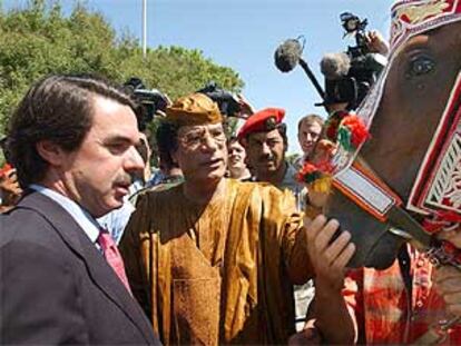 Muammar el Gaddafi muestra a José María Aznar el caballo de raza árabe que ha regalado al presidente español.