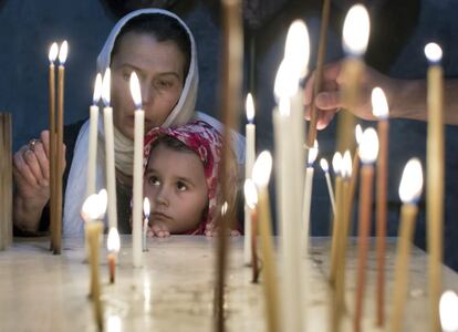 Una niña mira como su madre enciende unas velas en una capilla en Jerusalén 20 de abril de 2014.