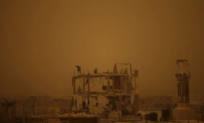 Obreros palestinos trabajan retirando los escombros de un edificio en la ciudad de Gaza durante una tormenta de arena.