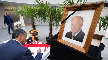 Un hombre escribe en el libro de condolencias dispuesto en el cementerio de Mouscron.