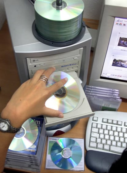 Una mujer introduce un CD virgen en una copiadora.