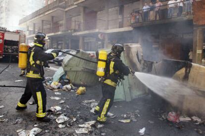 Los bomberos intentan apagar las llamas tras los destrozos provocados por los radicales.