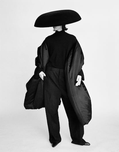 La modelo luce jersey de cuello alto tejido en vicuña negra, pantalón de sastre, estola acolchada en satén negro, guantes y botas, todo de la primera colección de alta costura de 1968 de la casa Balenciaga. Sombrero cúpula en terciopelo flocado negro de Philip Treacy.