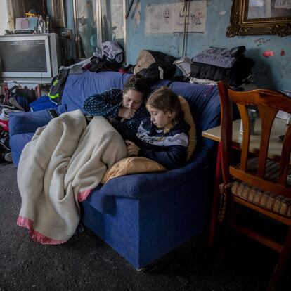A woman rests with her daughter inside their home at the Canada Real shanty town, outside Madrid, Spain, Tuesday, Jan. 12, 2021. Shops are flimsy set-ups with little stock and the residents live off construction jobs, scrap metal collection or whatever they can, and the area has long been associated with drugs. (AP Photo/Manu Fernandez)