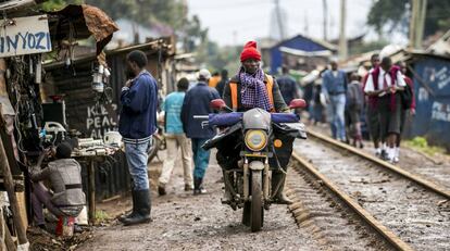 Un hombre conduce una moto junto a las vías de tren de Kibera, suburbio de Nairobi, la capital de Kenia.