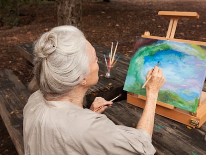 A woman paints a picture in the park. Scientific literature assures that cultivating hobbies such as painting is beneficial for health.