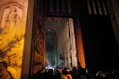 Miembros de la brigada de bomberos de París, en una entrada de la catedral de Notre Dame mientras el incendio continúa.