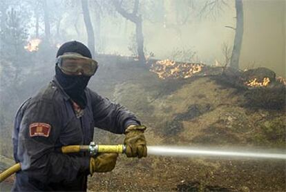 Un bombero trata de extinguir el incendio declarado esta tarde en Macanet de la Selva (Girona).