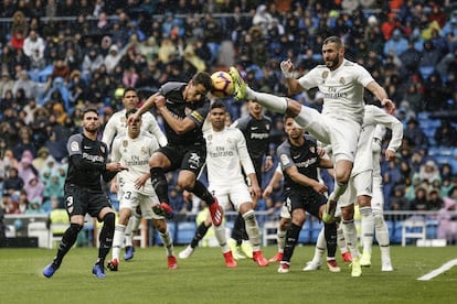 Wissam Ben Yedder intenta despejar el balón con la cabeza ante la bota de Karim Benzema.