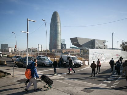 Diverses persones caminen prop de la torre Glòries i l'edifici del Disseny Hub a Barcelona.