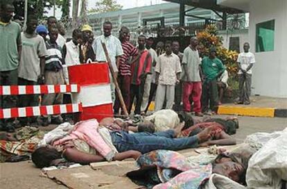 Varias personas observan los cadáveres de civiles muertos que buscaban refugio en la Embajada de EE UU en Monrovia.