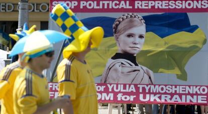 Aficionados ucranianos pasan ante un cartel de Timoshenko.